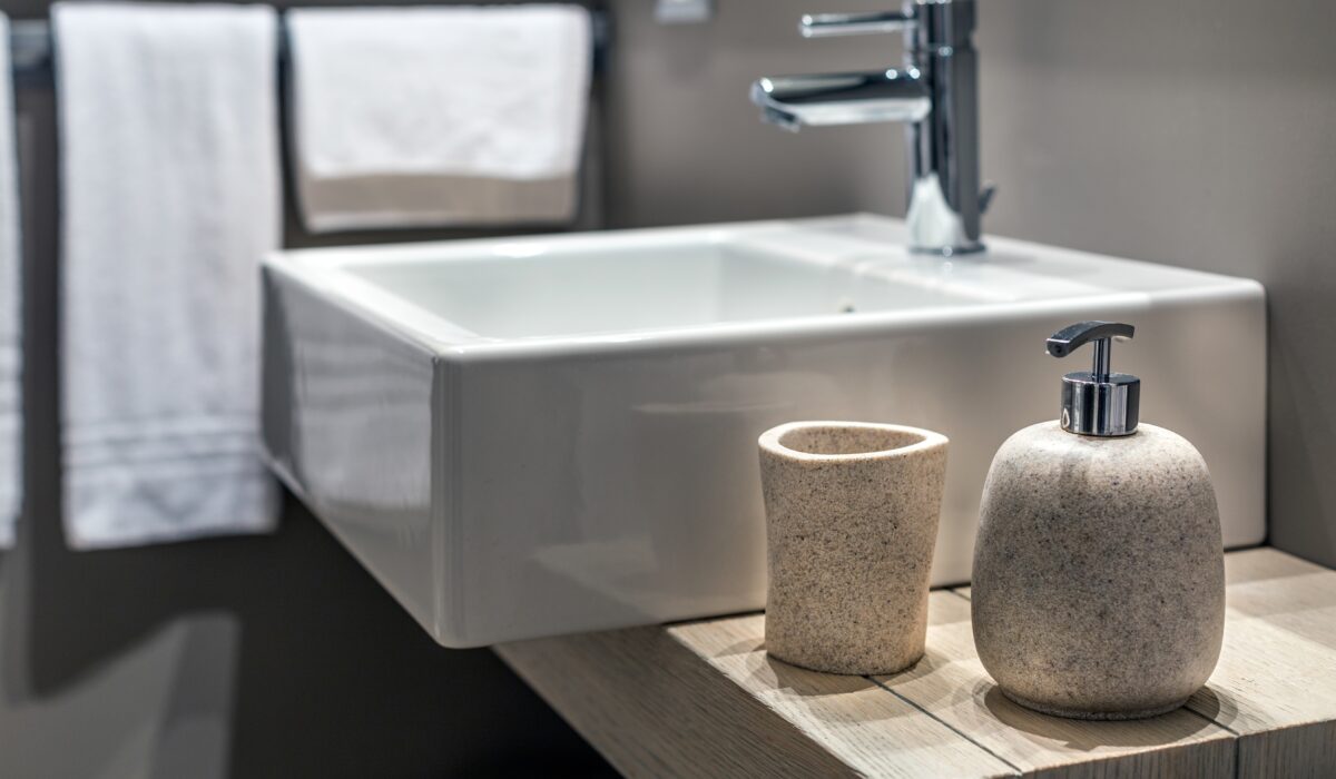 A shallow shot of a modern sink beside the bottle in the bathroom